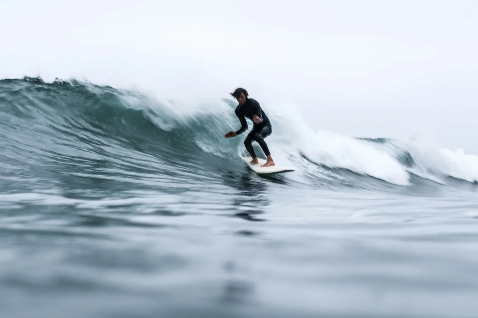 Surf coach guiding a student through pop-up practice on the beach